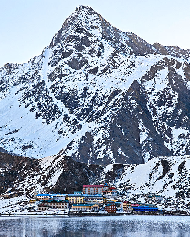 Edificios de colores junto a un lago bajo una gran montaña nevada