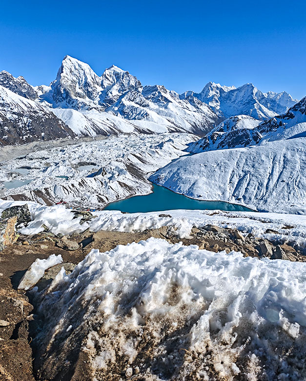 Lago turquesa y montañas nevadas vistos desde un sendero