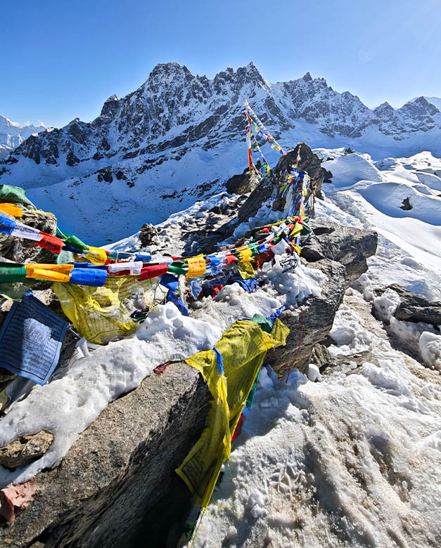 Banderas de oración entre nieve, rocas y montañas
